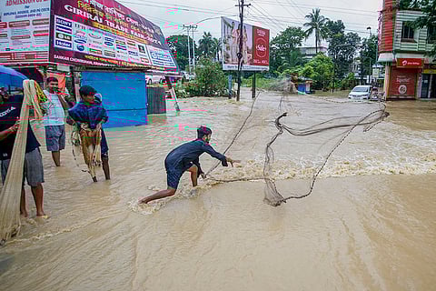 Flood in Tripura: A man casts a net to catch fish on a flooded road